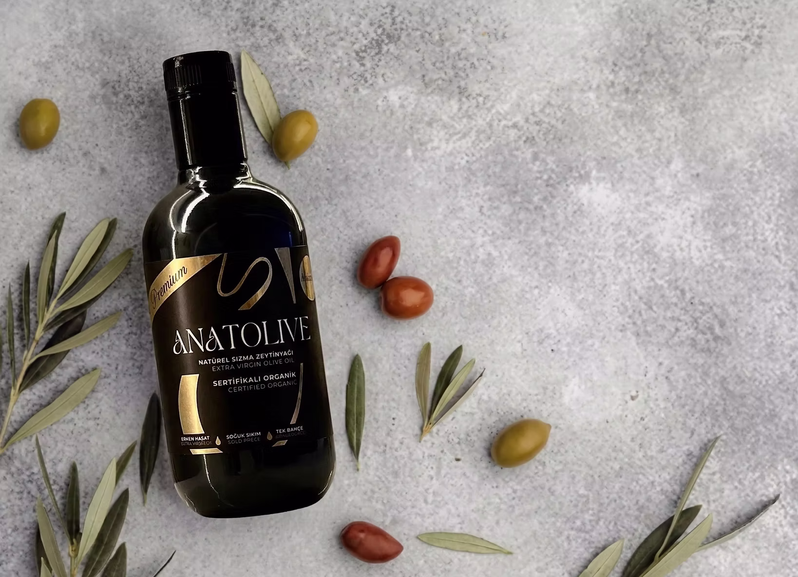 Anatolive natürel sızma zeytinyağı şişesi, zeytin daneleri ve dallar